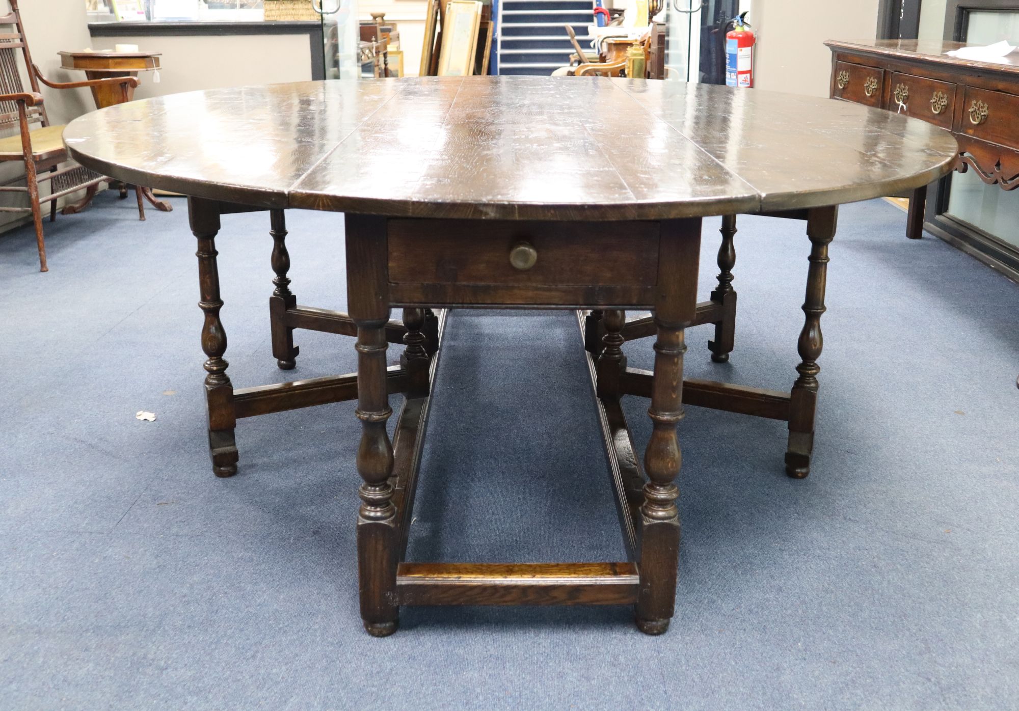 A late 17th century style oak oval topped, double gate leg dining table, width 214cm depth 180cm (extended) height 75cm